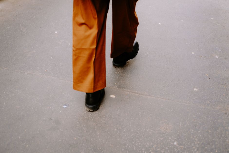 Close-up walking scene with black shoes and brown pants on a city street.