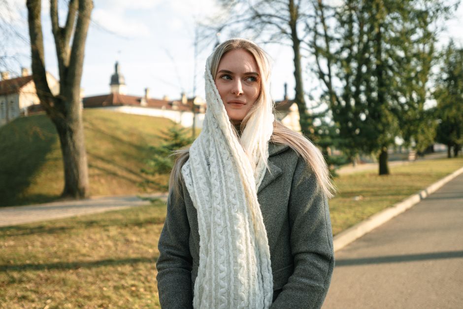 Woman in coat and scarf enjoying a sunny day in Нясвiж park, Беларусь.