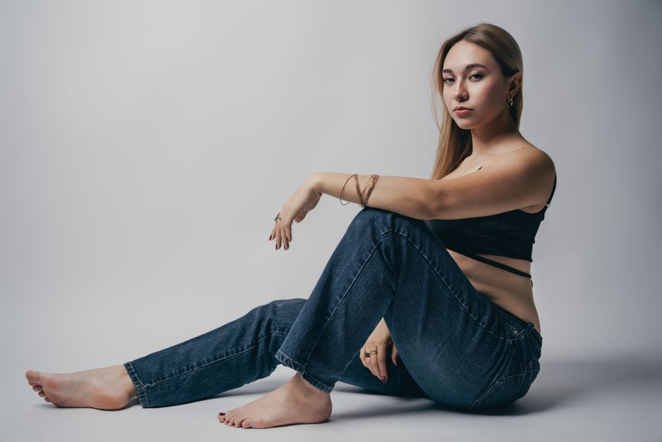 A modern portrait of a woman sitting comfortably wearing casual jeans and a stylish top.