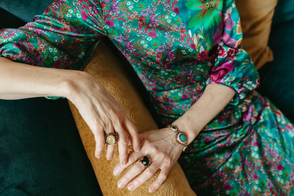 A vibrant floral dress paired with statement rings and bracelet, showcasing elegance and style.