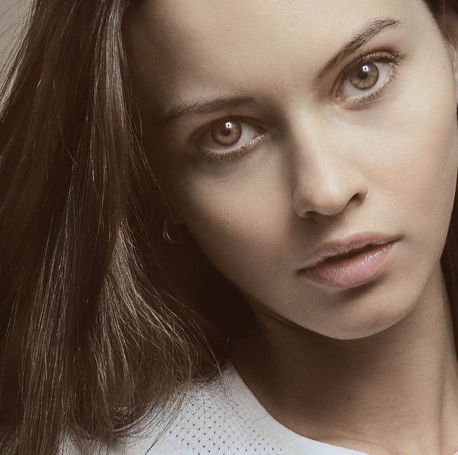 Artistic close-up portrait of woman with brown hair and soft expression.