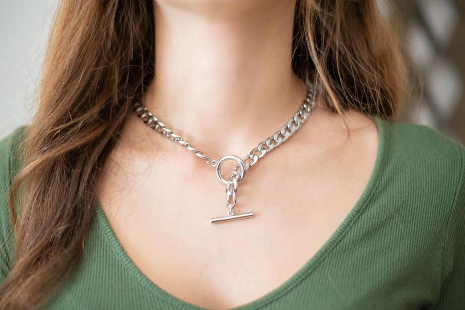 Close-up of a woman wearing a stylish silver necklace with a green top.