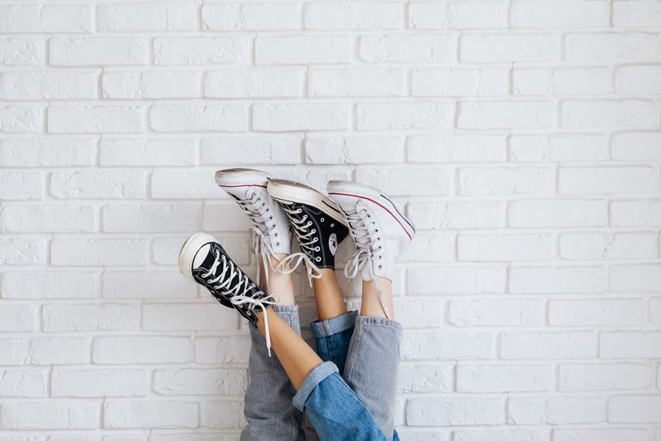 Fashion-forward sneakers displayed upside down against a white brick wall for stylish urban appeal.