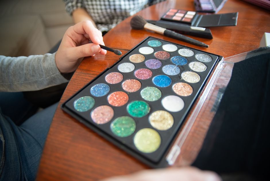 Vibrant glitter eyeshadows with makeup brushes on wooden table. Perfect for beauty and fashion themes.