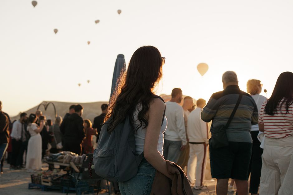 Crowd watching hot air balloons at sunrise in Cappadocia, Türkiye.